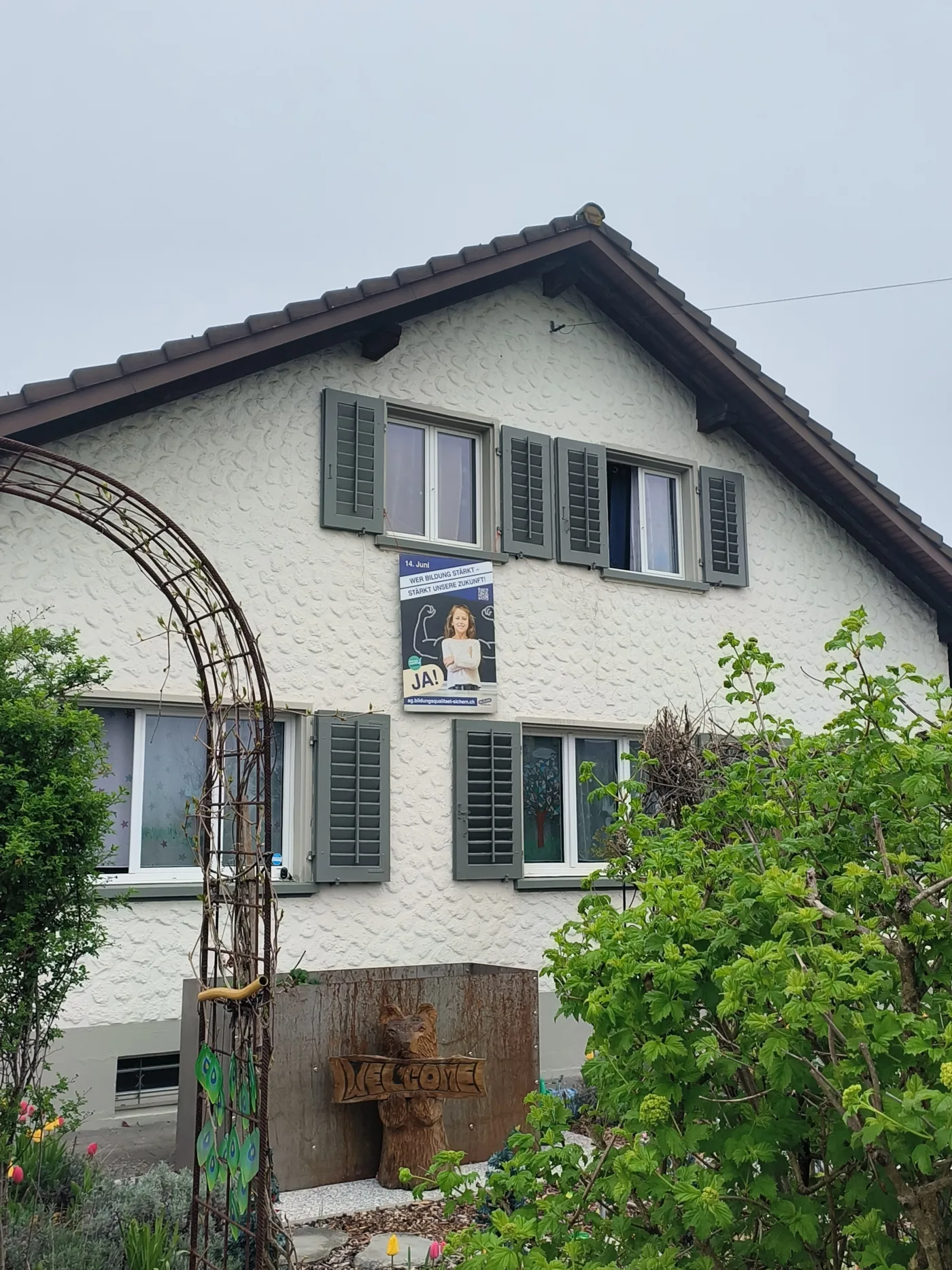 Das Bild zeigt ein Hausfassade mit einem Abstimmungsplakat, auf welchem für ein Ja zur Bildungsinitiative am 14. Juni geworben wird.