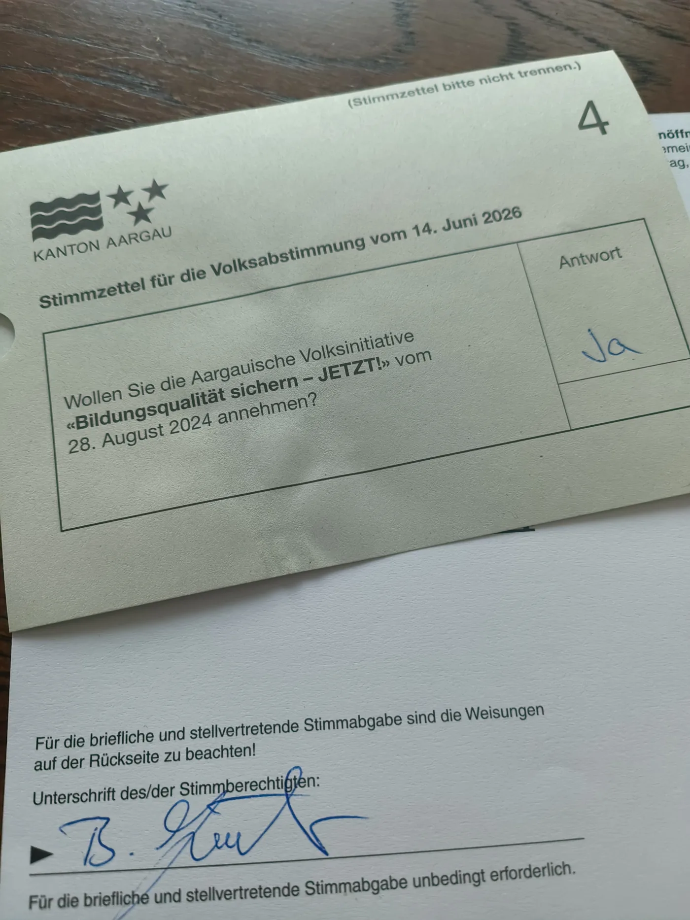 Das Bild zeigt einen Abstimmungszettel und einen Stimmrechtsausweis. Der Abstimmungszettel ist mit Ja beschriftet und der Stimmrechtsausweis unterschrieben.